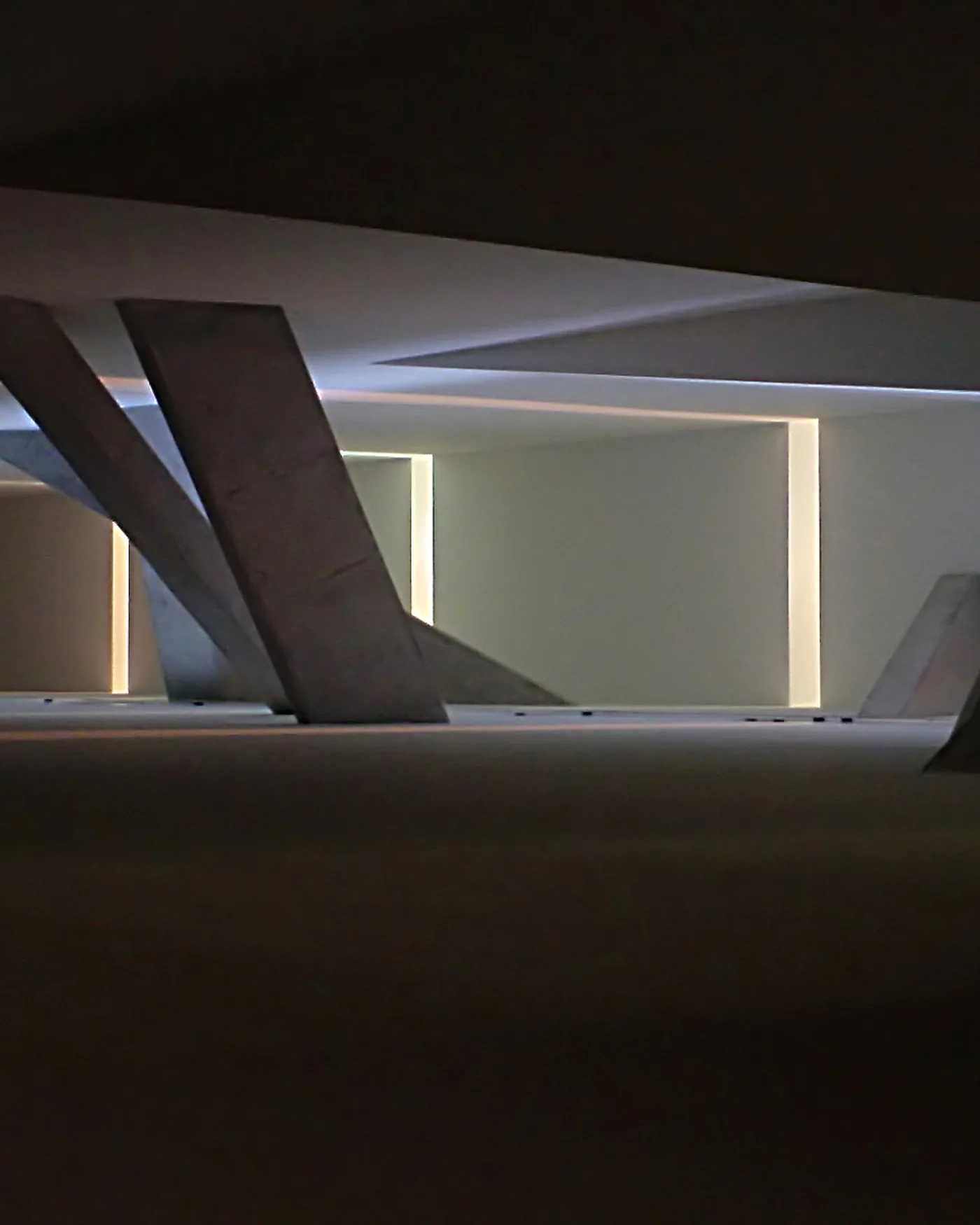 Dark angular concrete architectural interior with sculptural leaning columns