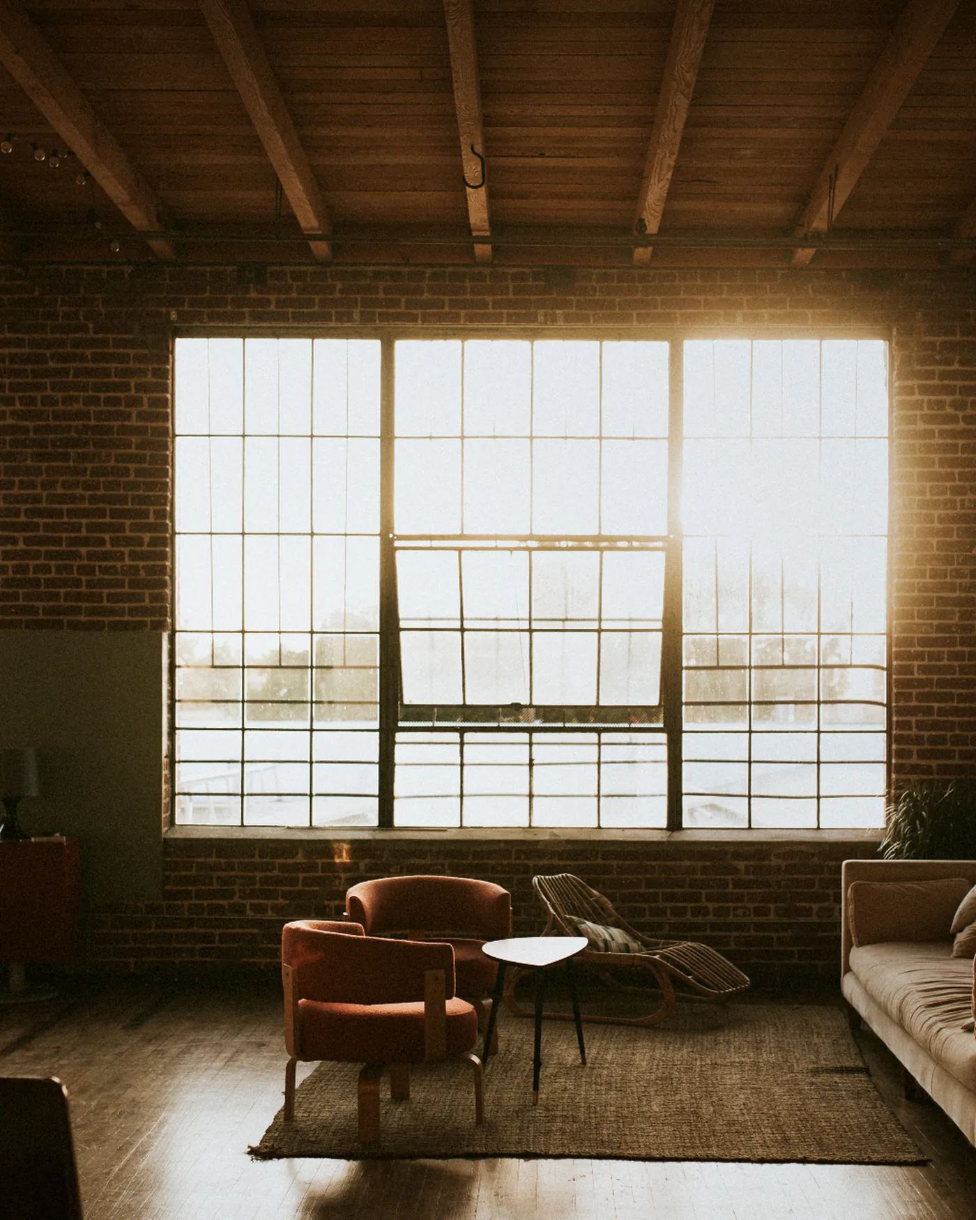 Warm industrial loft interior with tall grid windows glowing at golden hour